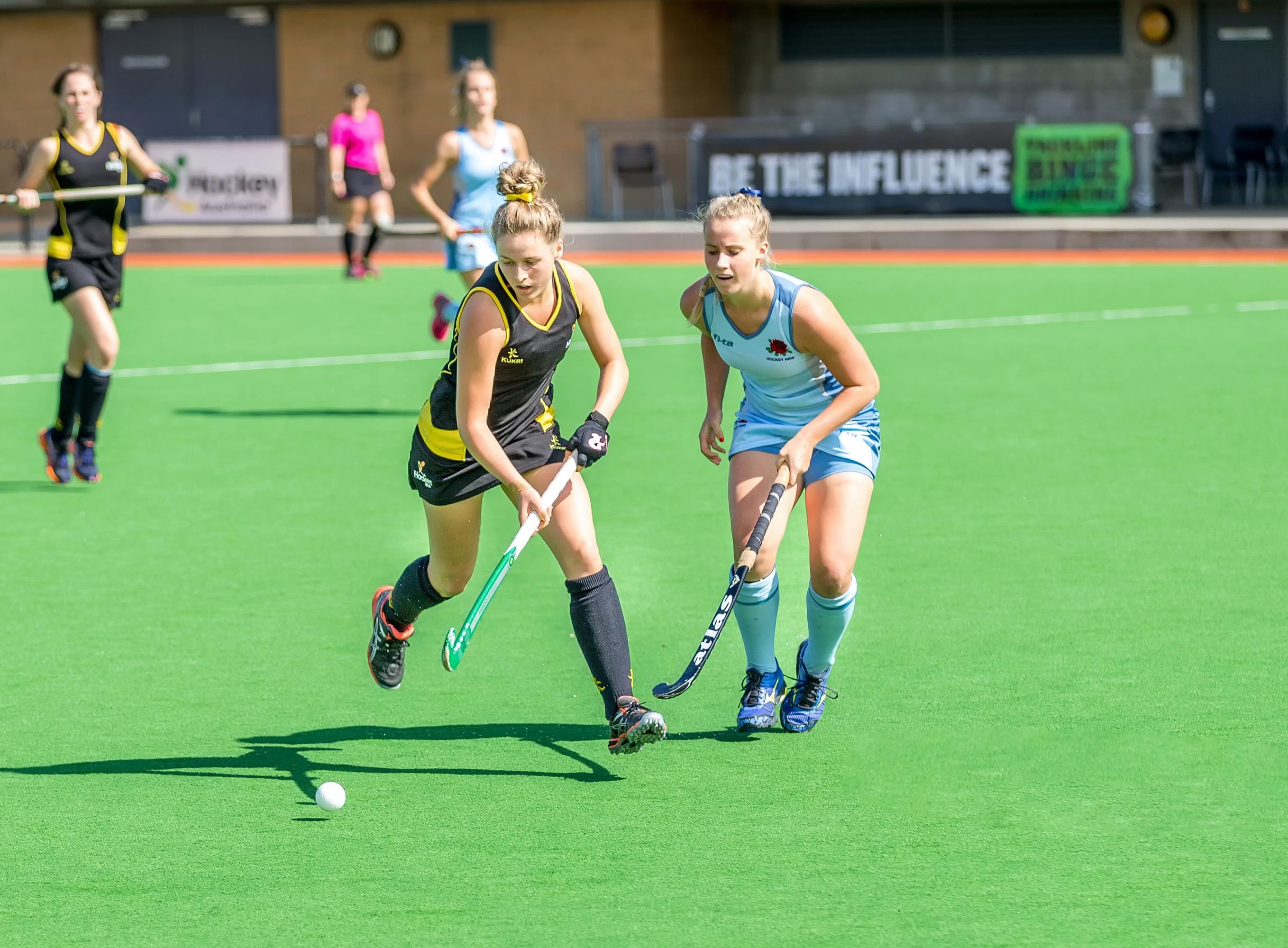 Women playing field hockey