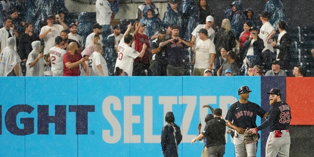 Boston Red Sox first base coach Tom Goodwin, second from left, calms left fielder Alex Verdugo (99) after he was hit in the back by an object thrown by a fan during the sixth inning of a baseball game against the New York Yankees, Saturday, July 17, 2021, in New York. (Associated Press)