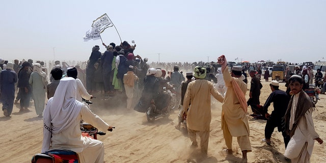 Supporters of the Taliban carry the Taliban's signature white flags in the Afghan-Pakistan border town of Chaman, Pakistan, Wednesday, July 14, 2021. (AP Photo/Tariq Achkzai)