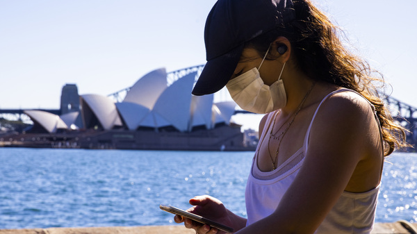 A woman looks at her phone outside the The Royal Botanic Gardens in Sydney, Australia on Aug. 6. The Indicator from Planet Money spoke to an economist for advice on how to cut back on digital dependency.