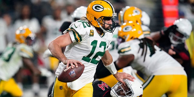 Green Bay Packers quarterback Aaron Rodgers (12) pushes down Arizona Cardinals linebacker Markus Golden (44) during the first half of an NFL football game, Thursday, Oct. 28, 2021, in Glendale, Ariz. 