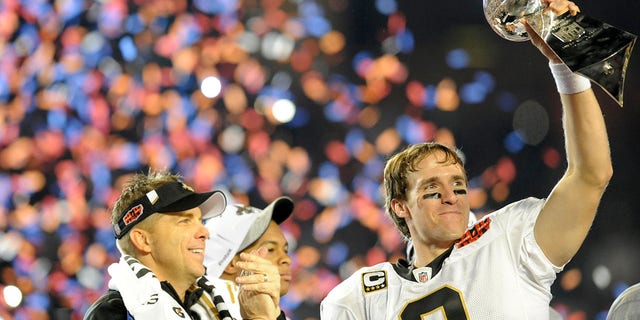 Drew Brees of the New Orleans Saints hoists the Vince Lombardi Trophy on the podium as head coach Sean Payton looks on after they defeated the Indianapolis Colts in the Super Bowl Feb. 7, 2010, at Sun Life Stadium in Miami Gardens, Fla. 