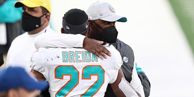 Head coach Brian Flores of the Miami Dolphins hugs Matt Breida on the sidelines during their NFL game against the New York Jets at MetLife Stadium on Nov. 29, 2020, in East Rutherford, New Jersey.