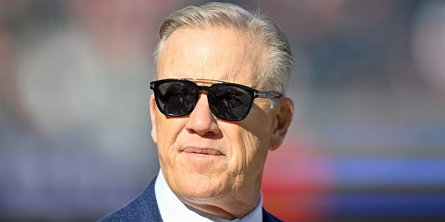 John Elway, president of football operations for the Denver Broncos, stands on the field before a game between the Broncos and the Cincinnati Bengals at Empower Field at Mile High on Dec. 19, 2021, in Denver, Colorado.