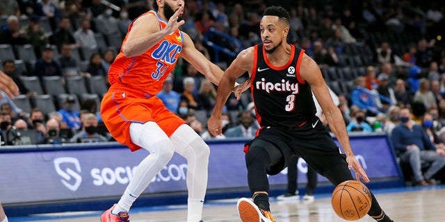 Portland Trail Blazers guard CJ McCollum, right, drives against Oklahoma City Thunder forward Kenrich Williams in the first half of an NBA basketball game Monday, Jan. 31, 2022, in Oklahoma City.