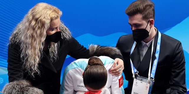 Kamila Valieva of Team ROC reacts to their score with choreographer Daniil Gleikhengauz (R) and coach Eteri Tutberidze (L) after the Women Single Skating Free Skating on day thirteen of the Beijing 2022 Winter Olympic Games at Capital Indoor Stadium on Feb. 17, 2022 in Beijing, China.