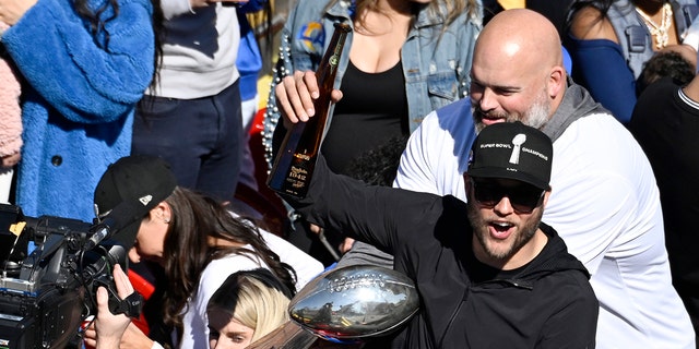 Los Angeles Rams quarterback Matthew Stafford holds up a bottle as offensive lineman Andrew Whitworth, right, holds the Vince Lombardi Super Bowl trophy during the team's victory parade in Los Angeles, Wednesday, Feb. 16, 2022, following their win Sunday over the Cincinnati Bengals in the NFL Super Bowl 56 football game.