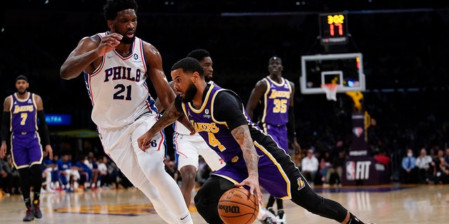 Philadelphia 76ers center Joel Embiid (21) defends against Los Angeles Lakers guard D.J. Augustin (4) during the first half of an NBA basketball game in Los Angeles, Wednesday, March 23, 2022.