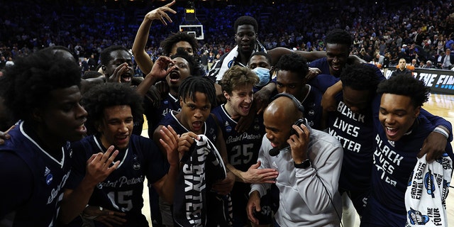 St. Peter's Peacocks players celebrate with head coach Shaheen Holloway after defeating the Purdue Boilermakers 67-64 in the Sweet Sixteen round game of the 2022 NCAA Men's Basketball Tournament at Wells Fargo Center on March 25, 2022 in Philadelphia, Pennsylvania.