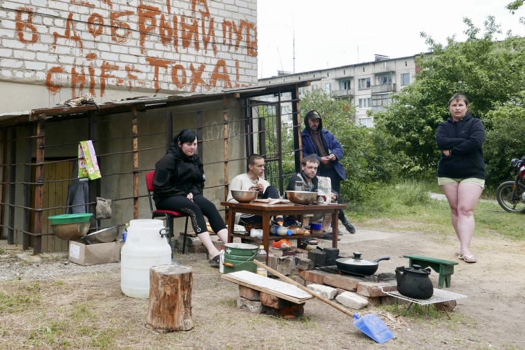 A family cooks a meal outside their home in Siversk, Ukraine, where the power and running water have been out for weeks.