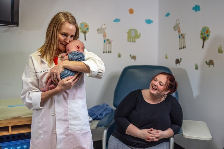 Director of the maternal and infant research lab at Pennington Biomedical Research Center Doctor Leanne Redman, left, holds Jameson, son of Julie Hardee, right, at the Pennington Biomedical Research Center at Louisiana State University in Baton Rouge on May 12, 2022.