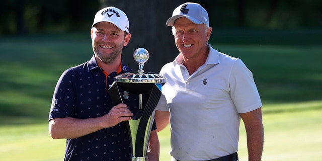 Branden Grace, left, and LIV Golf CEO Greg Norman, right, pose with the trophy after Grace won the Portland Invitational LIV Golf tournament in North Plains, Ore., July 2, 2022. 