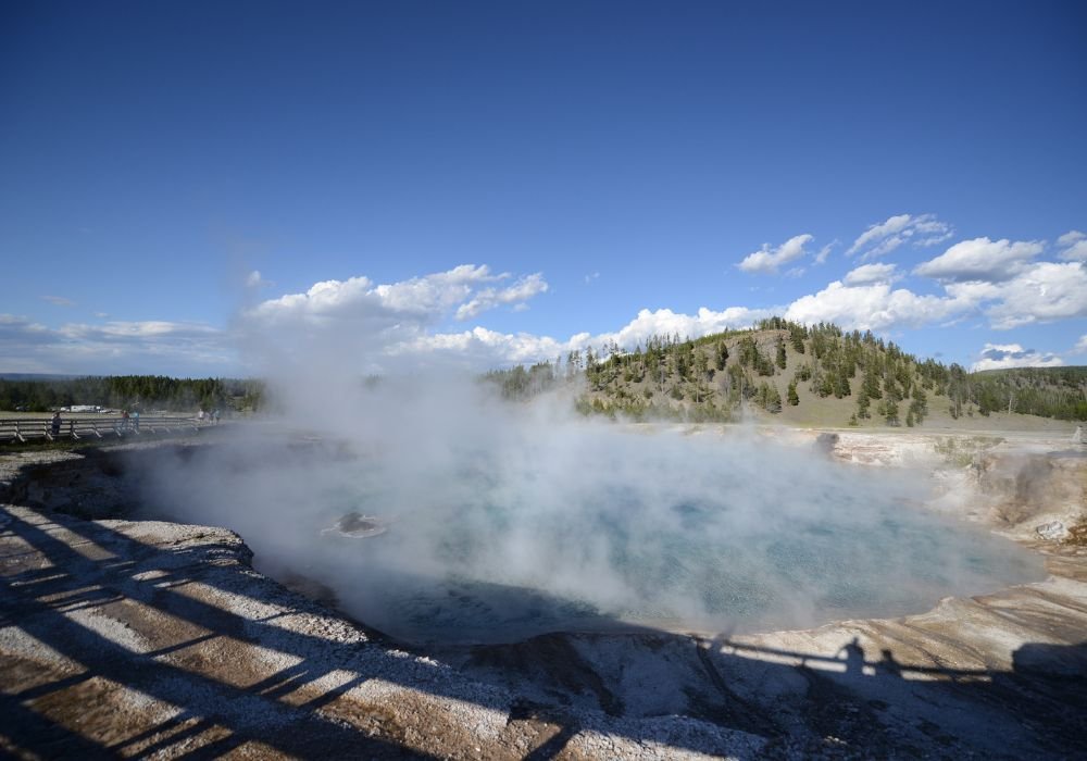 A view of a small hot spring with rising steam at Yellowstone National Park