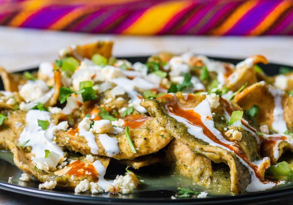 A chilaquiles verdes on a ceramic black plate.