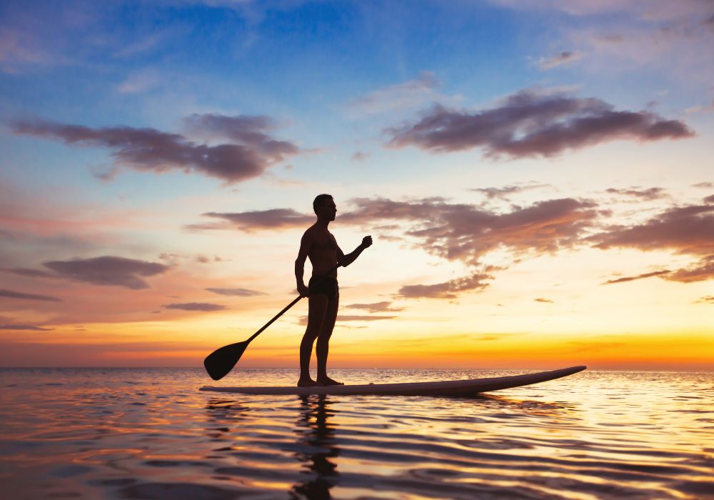 A beautiful silhouette of a man at sunset during stand-up paddleboarding.