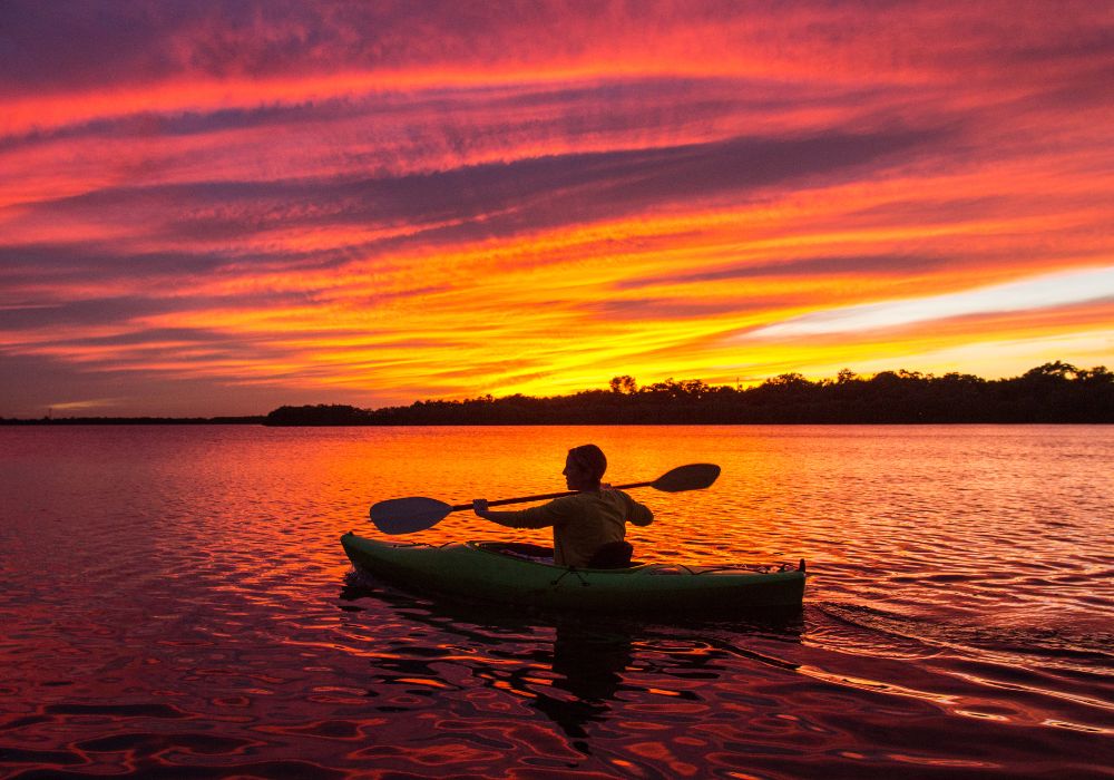 A person kayaking with a beautiful non-filtered sunset.