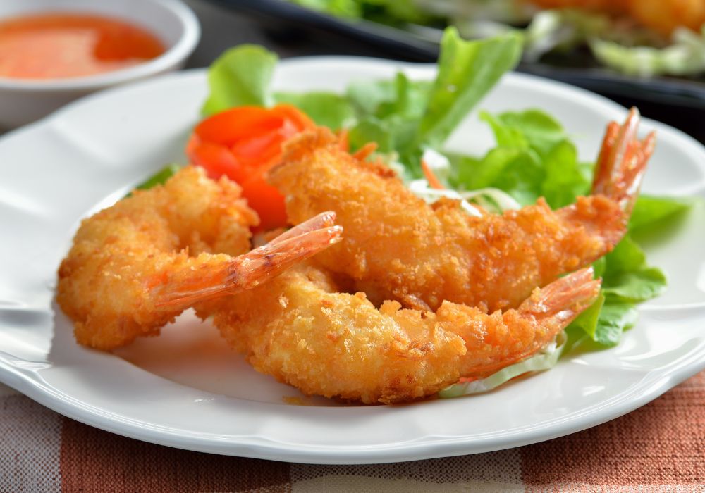 Camarones empanizados are served on a white plate with a side dish.