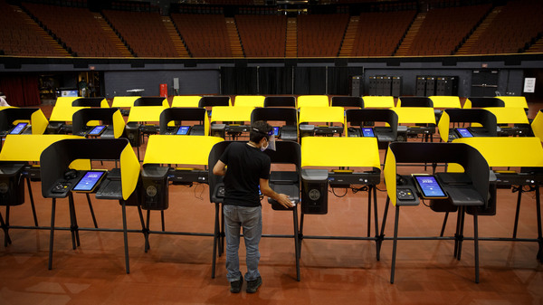 A poll worker sanitizes ballot marking machines at an early voting location in Inglewood, Calif., on Oct. 29, 2020. The Los Angeles County district attorney alleges that the CEO of Konnech, which makes scheduling software for poll workers, improperly gave Chinese contractors access to sensitive employee data.