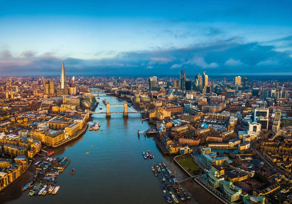 Panoramic aerial skyline view of London including Tower Bridge along Thames River.