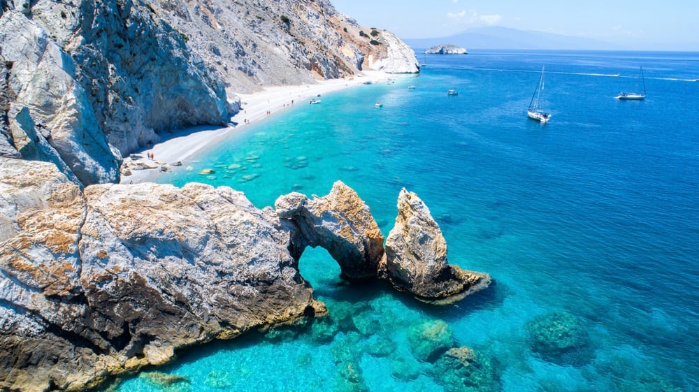 The tall cliffs and sky-blue water in Lalaria, Skiathos, one of the nicest beaches in Greece