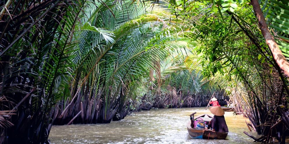 Riding in a boat down narrow passages of water in the Mekong Delta, Vietnam