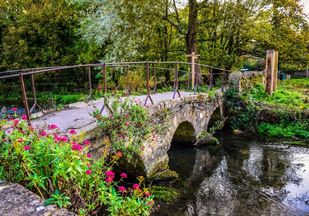 Old stone bridge over river Coln at Bibury village in Cotswold, UK.