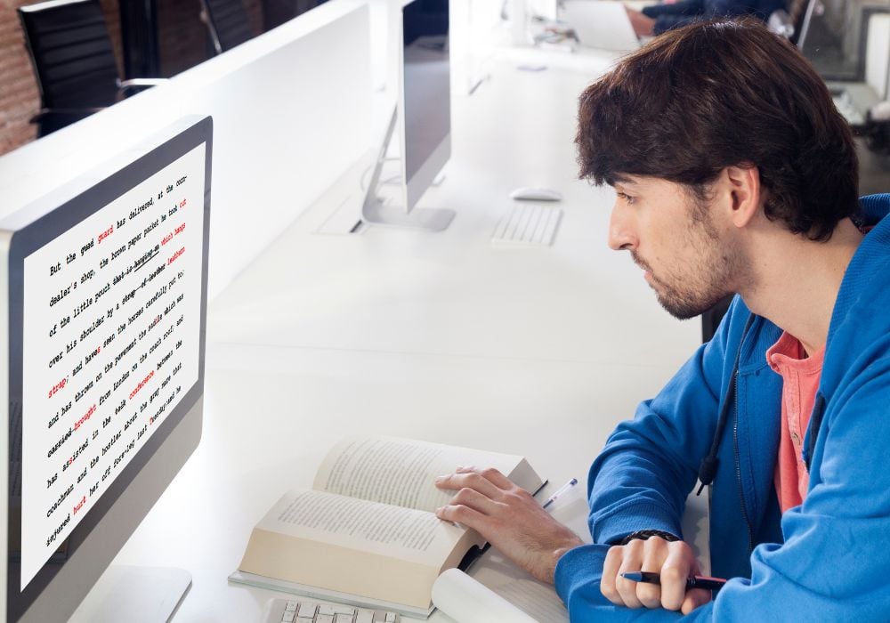 A young man is proofreading and editing on his computer.