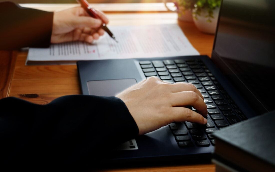 Hand working on editing blurry text with a pen and computer on the desk