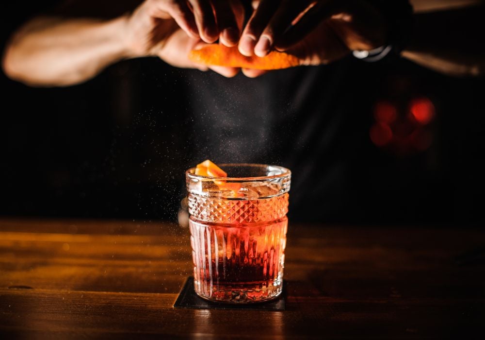 Bartender with cocktail with orange at the bar.