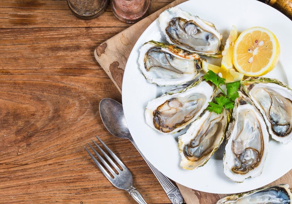 A plate of six oysters on a wooden table