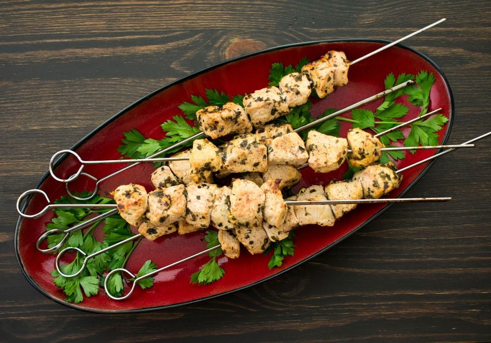 A platter of chicken souvlaki on a wooden table