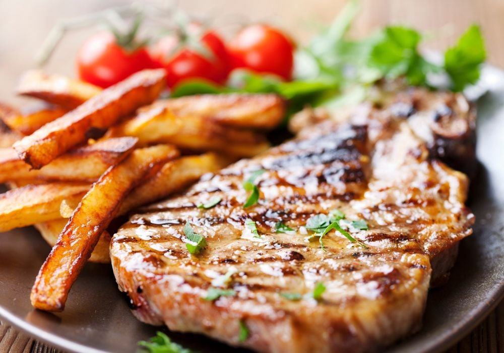 Grilled mongolian pork chop with french fries on a platter