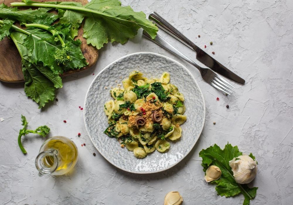 Delicious orecchiette on a ceramic plate with herbs and olive oil on the table