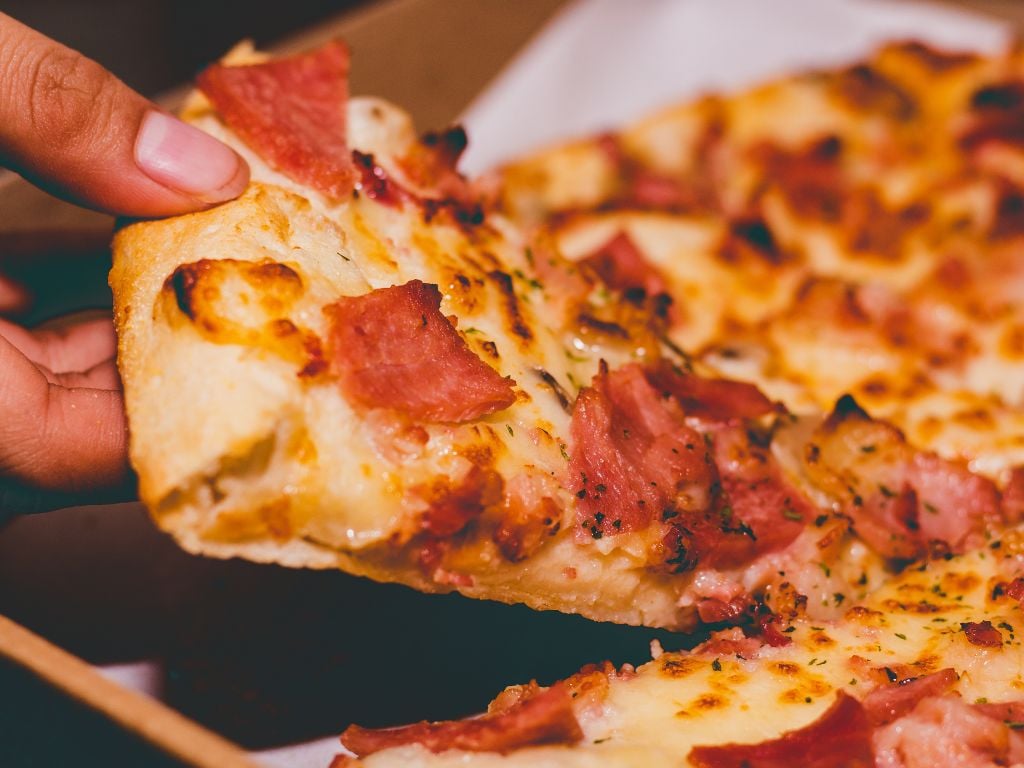 person pulling a slice of pizza