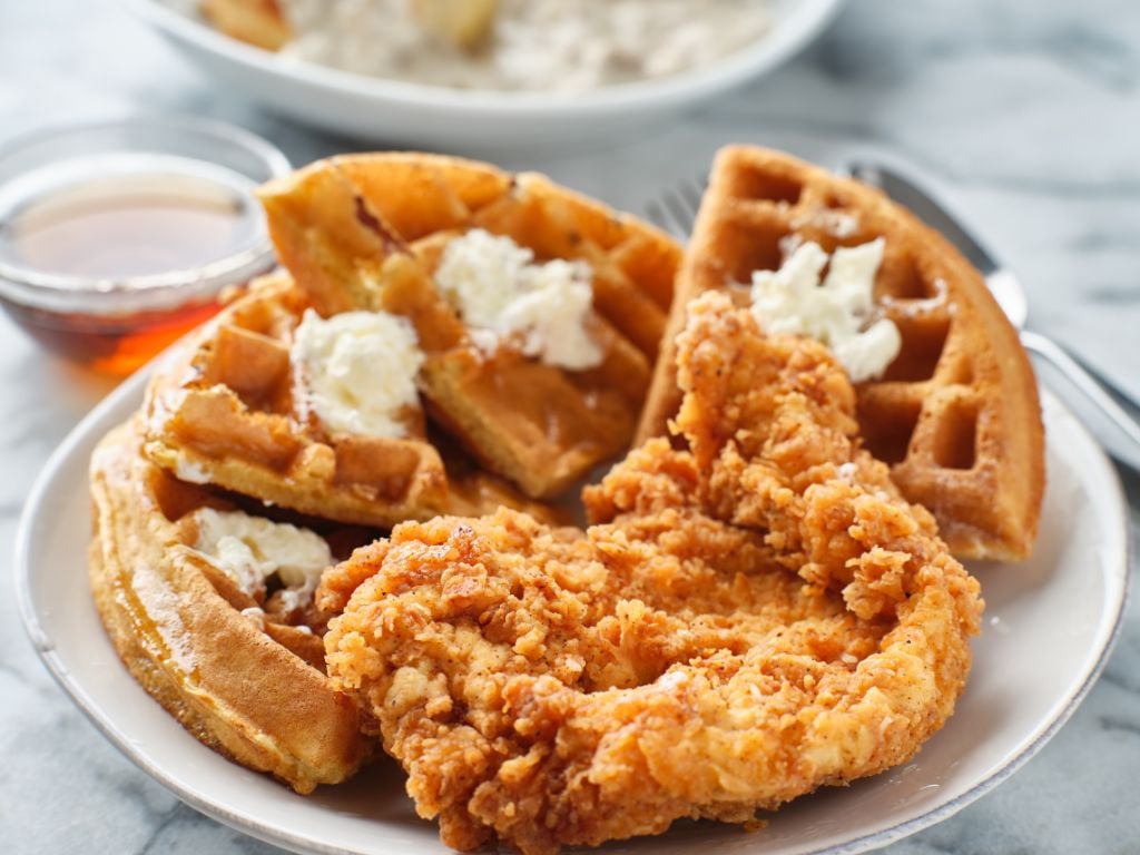 plate with chicken and waffles and whip cream