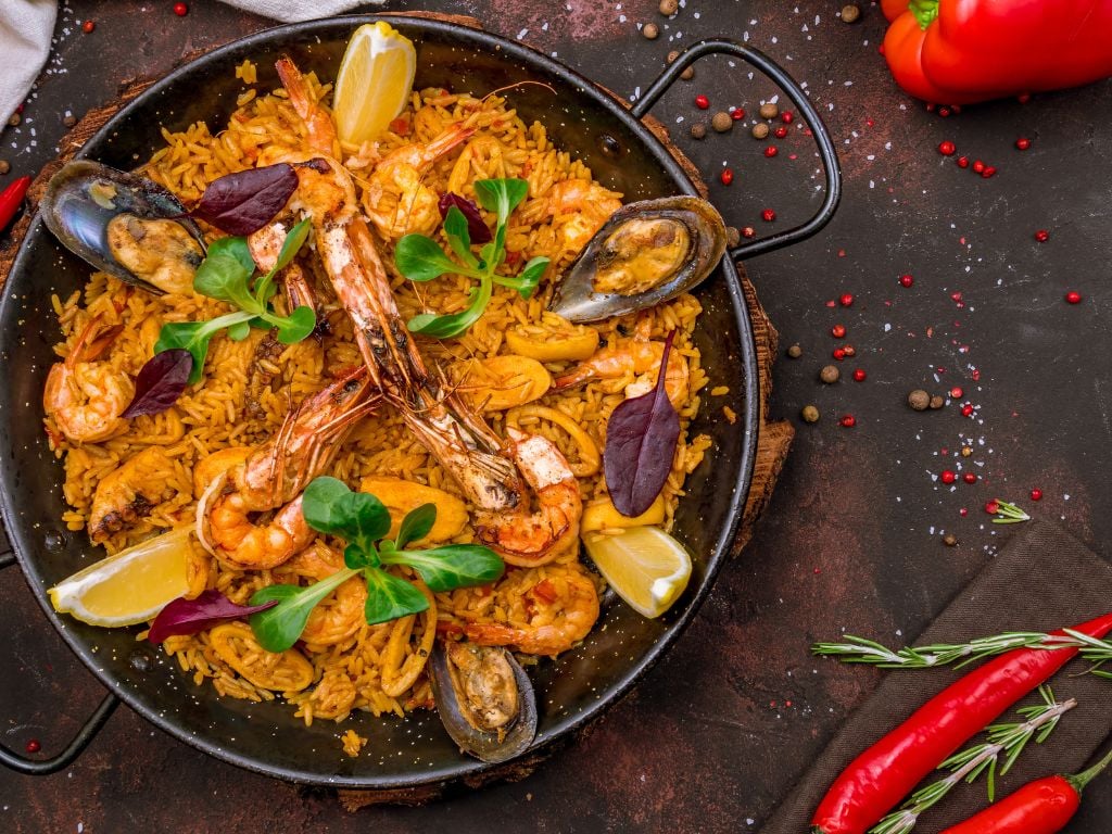 a pan with paella and fresh seafood on top
