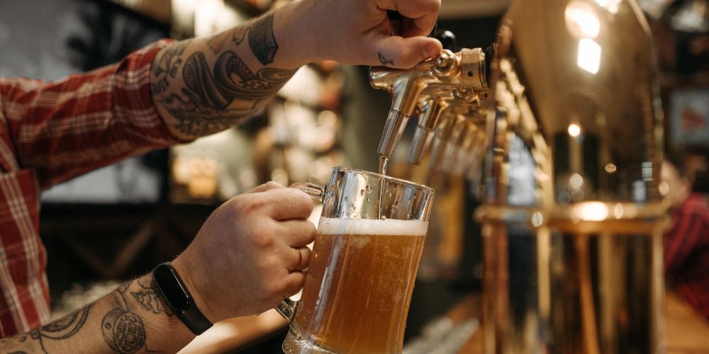 man pouring a beer from a tap at a brewery