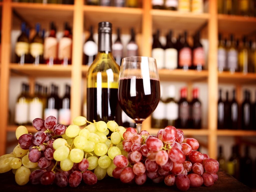 wine glass with grapes and bottles of wine