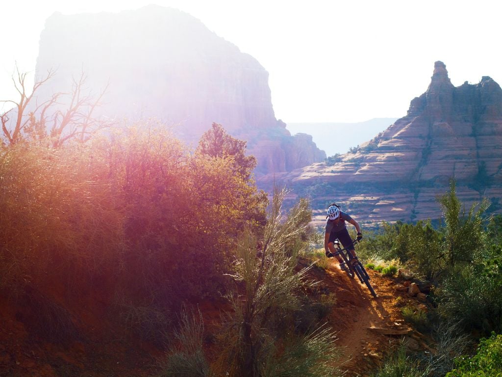 man mountain biking in sedona with mountains behind him