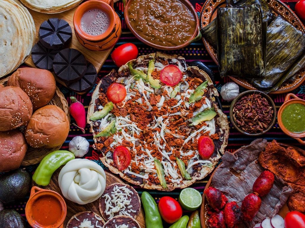 table full of bright mexican food, cheese, jalapenos, meats and chocolate