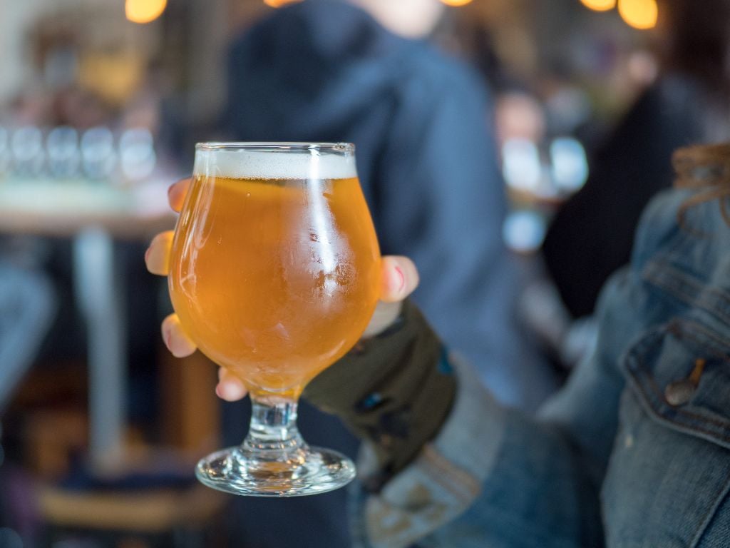 a woman holding an IPA beer in a glass