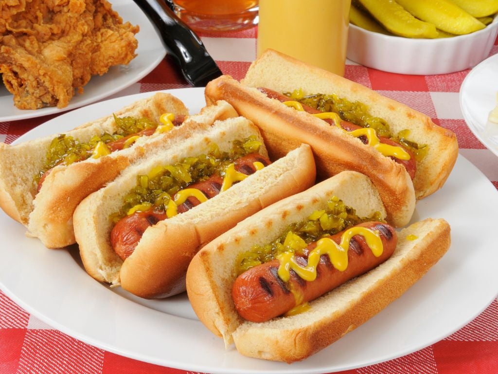 a plate full of hotdogs with mustard and relish