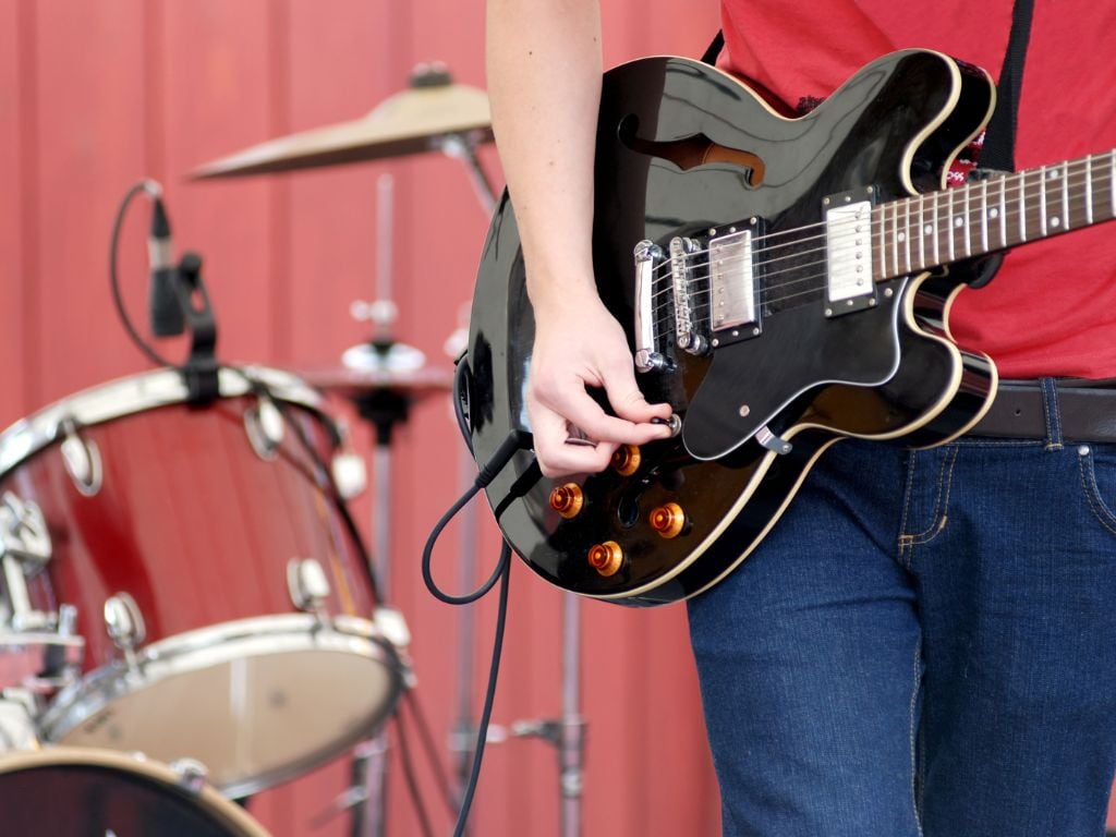 man playing a guitar with drums in the background