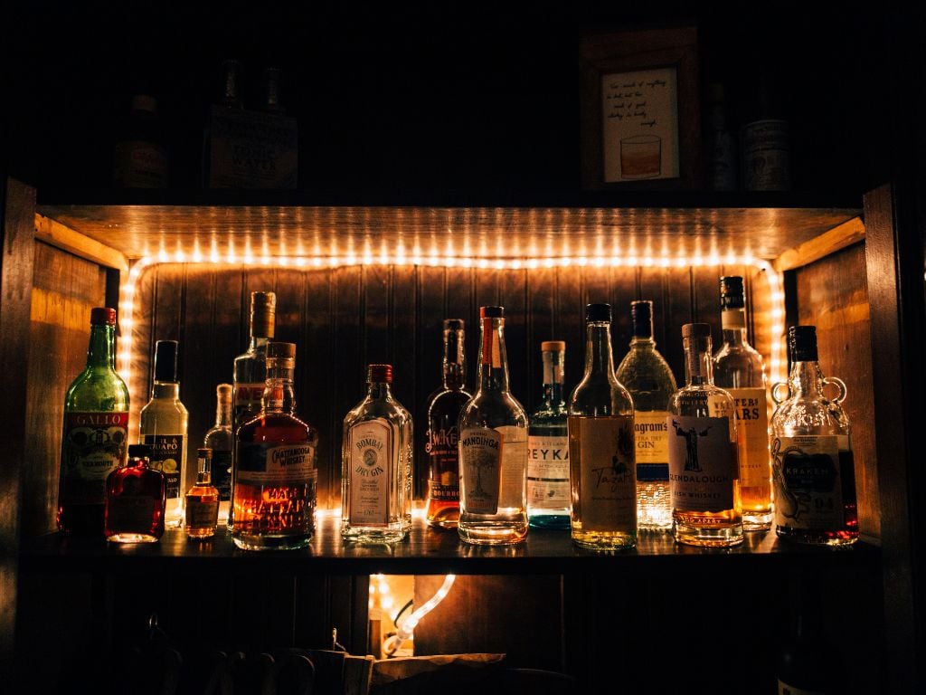 a lot of whiskey bottles lit up in a bar