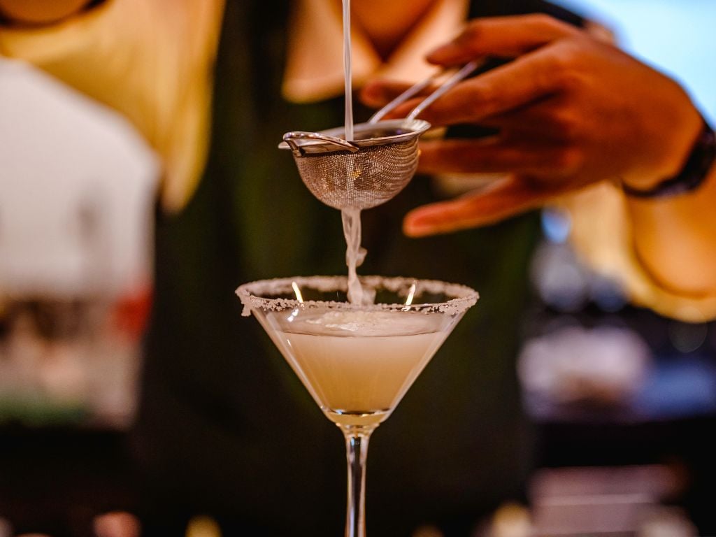 bartender pouring a cocktail through a strainer