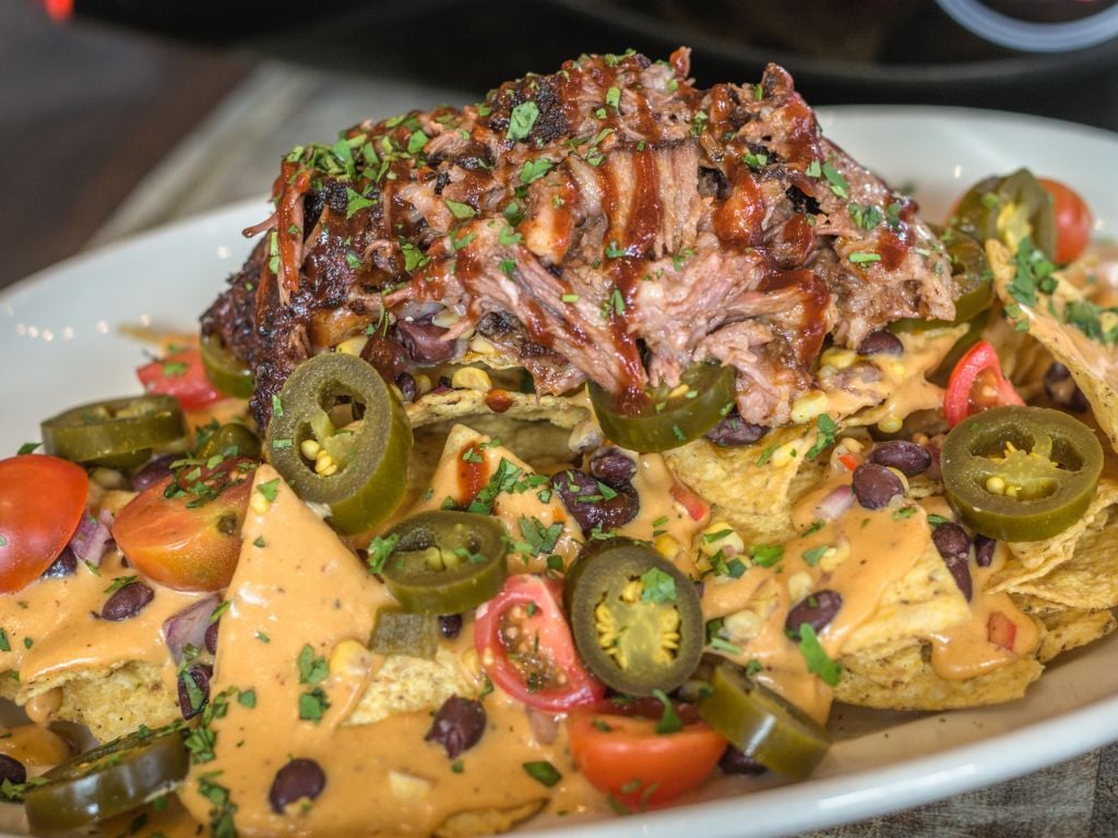 a plate full of brisket nachos with jalapenos and cheese