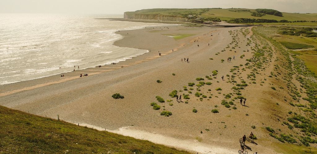 Cuckmere Haven Beach with grayish sand, plants and hills
