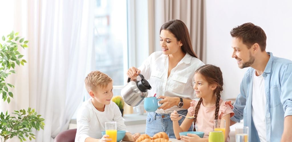 Family Eating Breakfast Together with one son and one daughter and cups 