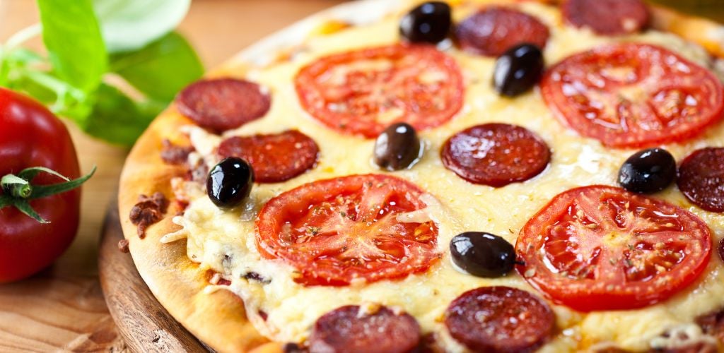 Stonebaked pizza with chorizo salami with tomato on a wooden table