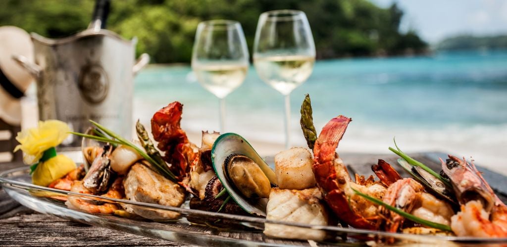 Seafood at a restaurant with white wine and beach in the background.